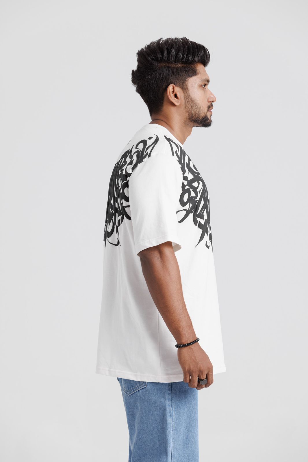 Man wearing a white t-shirt with black tribal design on a plain background