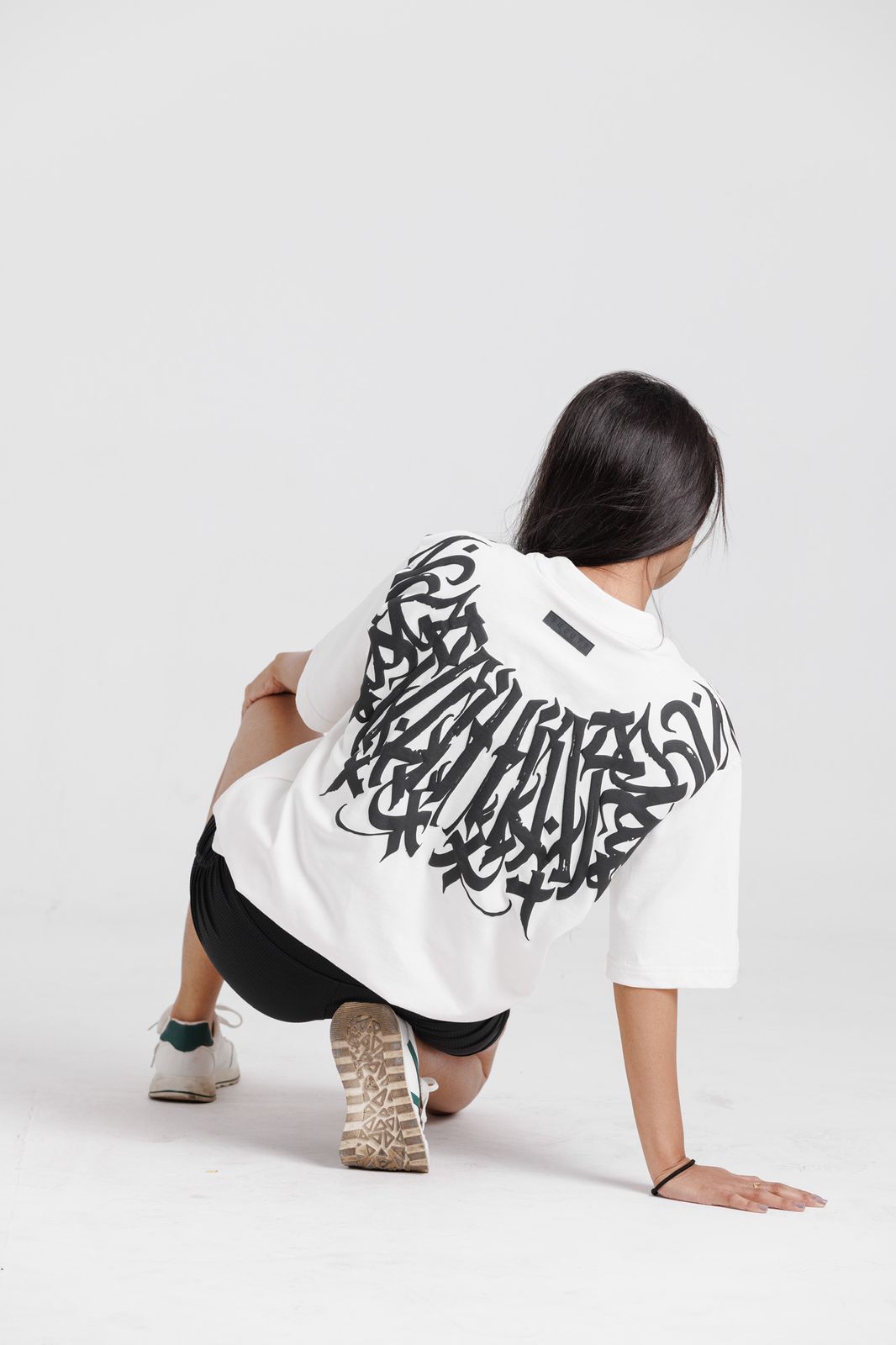 Person wearing a white hoodie with black abstract design on a light gray background