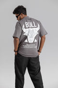 Person wearing a gray t-shirt with a bull graphic and text on the back, standing against a plain background.