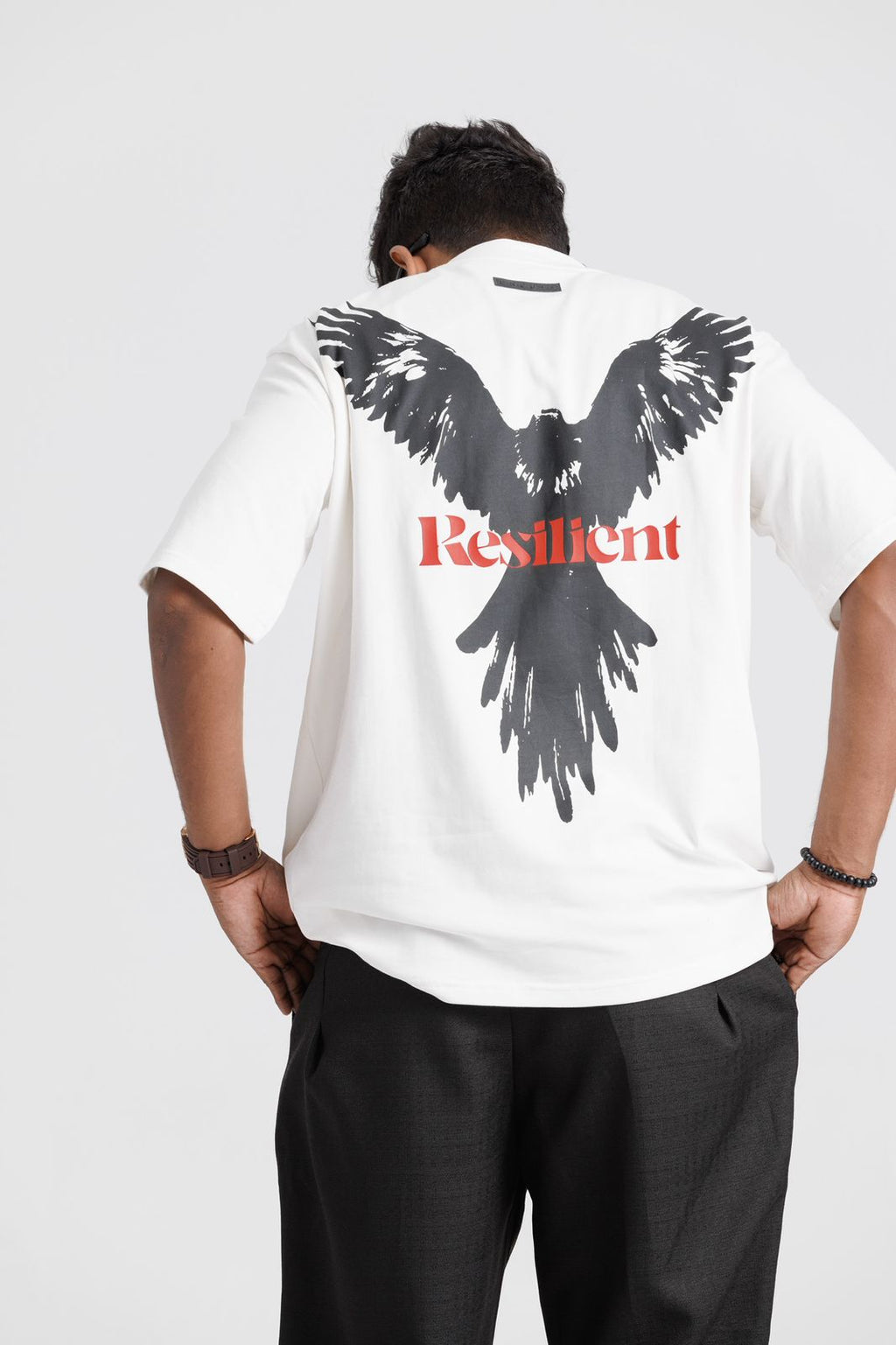 Person wearing a white t-shirt with an eagle graphic and the word 'Resilient' on the back.