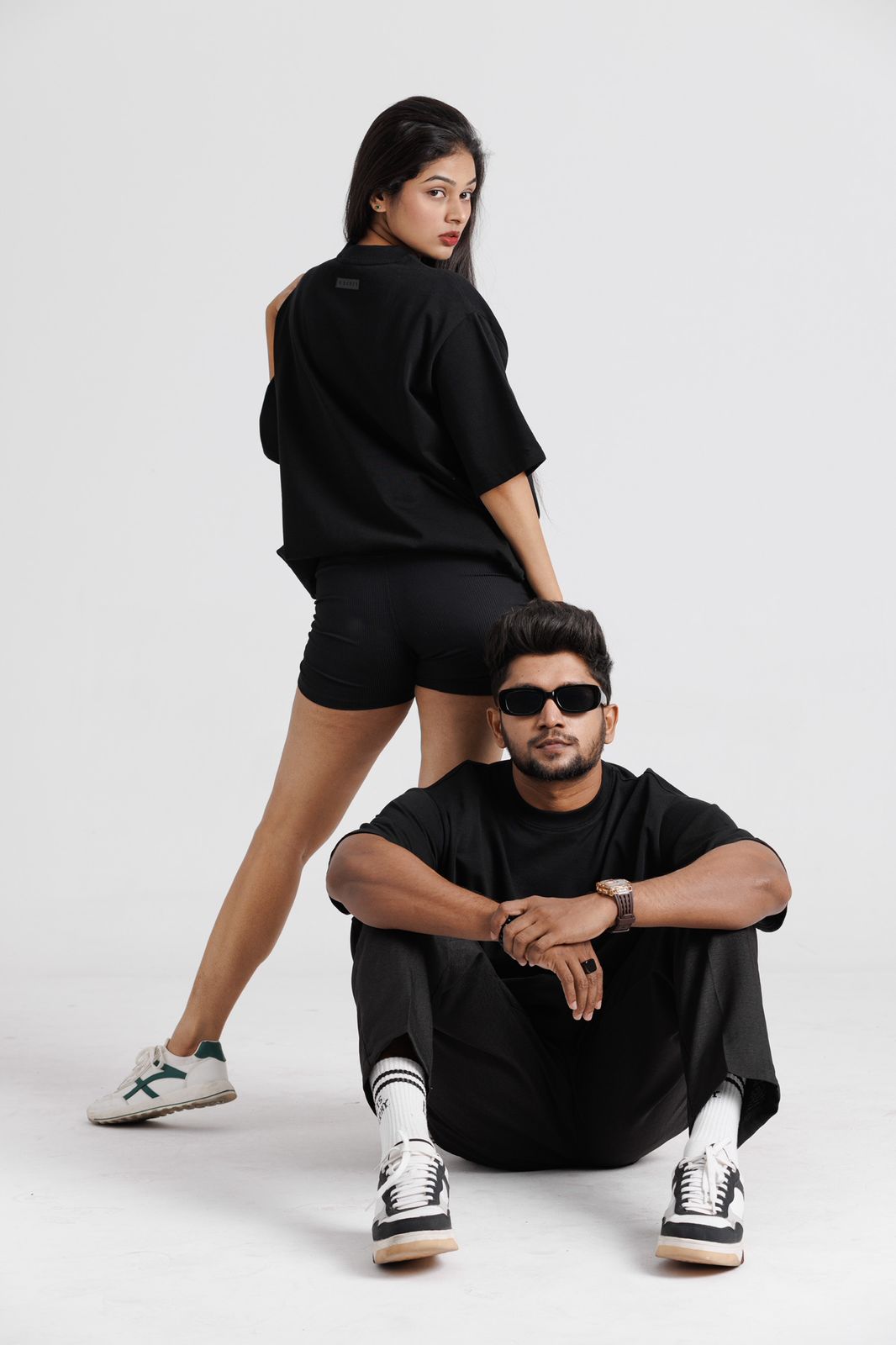 Two people wearing black outfits on a white background