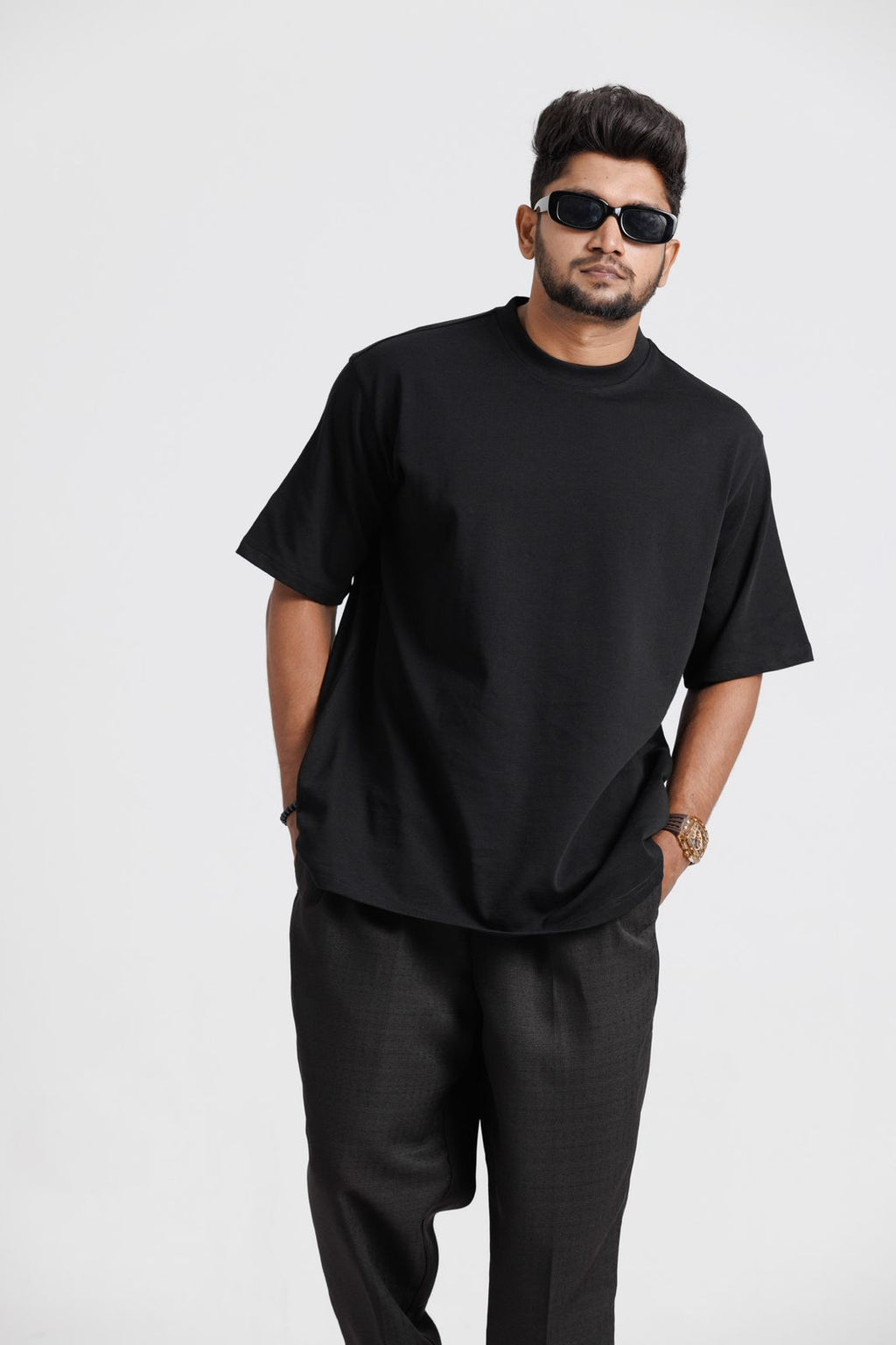 Man wearing a black t-shirt and pants with sunglasses on a white background