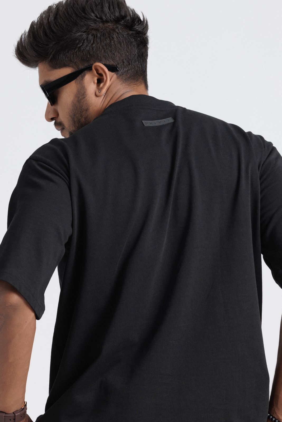 Man wearing a black t-shirt with sunglasses on a light gray background