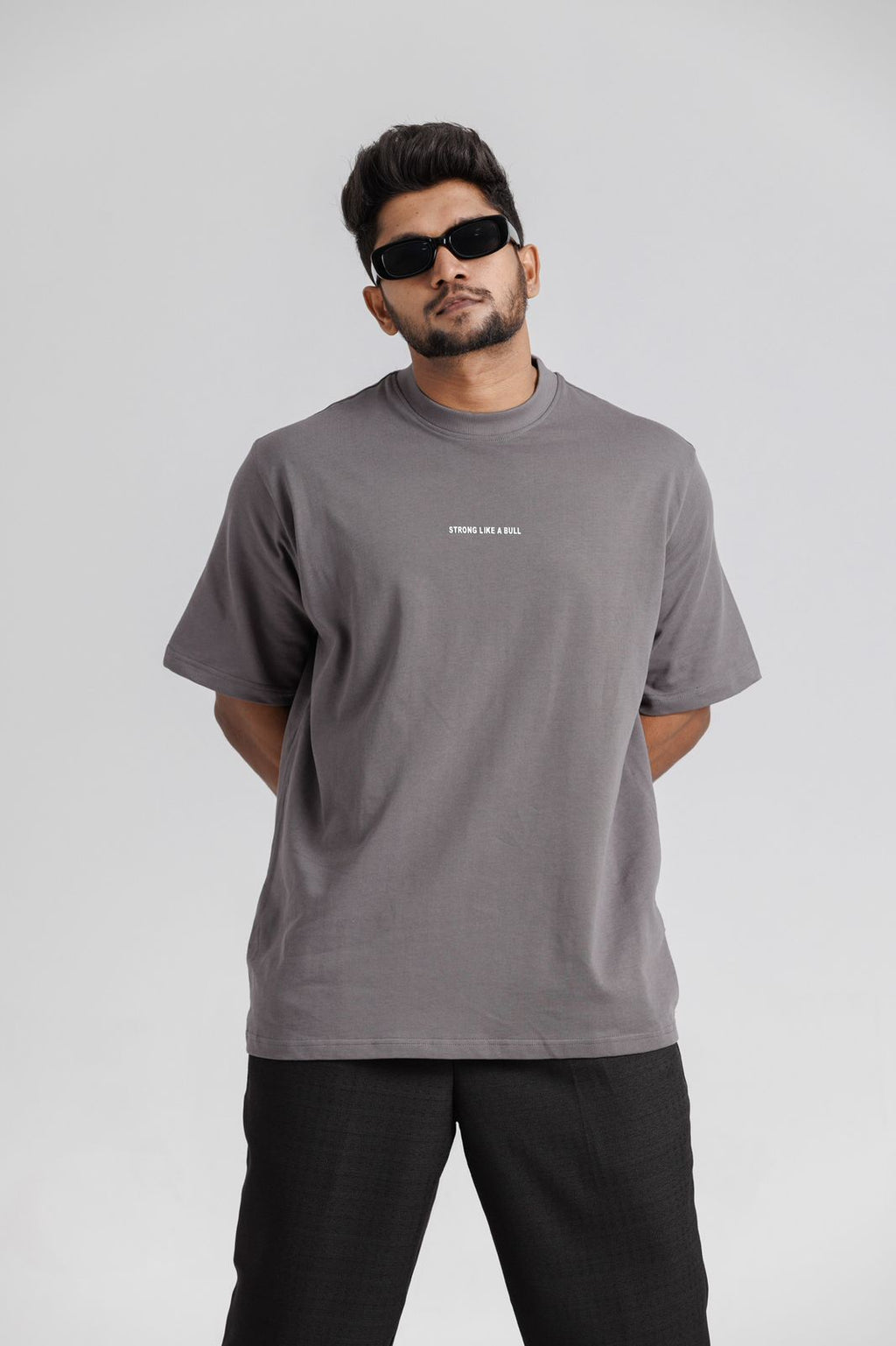 Man wearing a gray t-shirt with text on a plain background