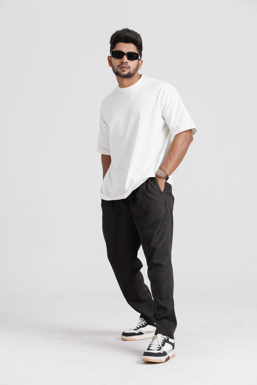 Man wearing a white t-shirt, black pants, and black sneakers on a white background