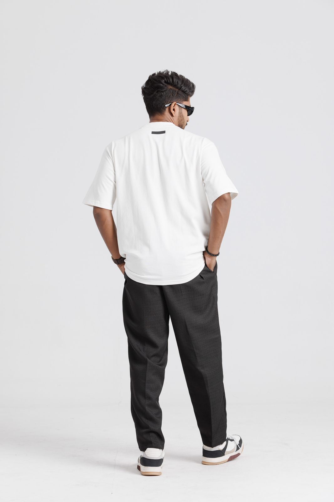 Person wearing a white polo shirt and black pants on a light gray background