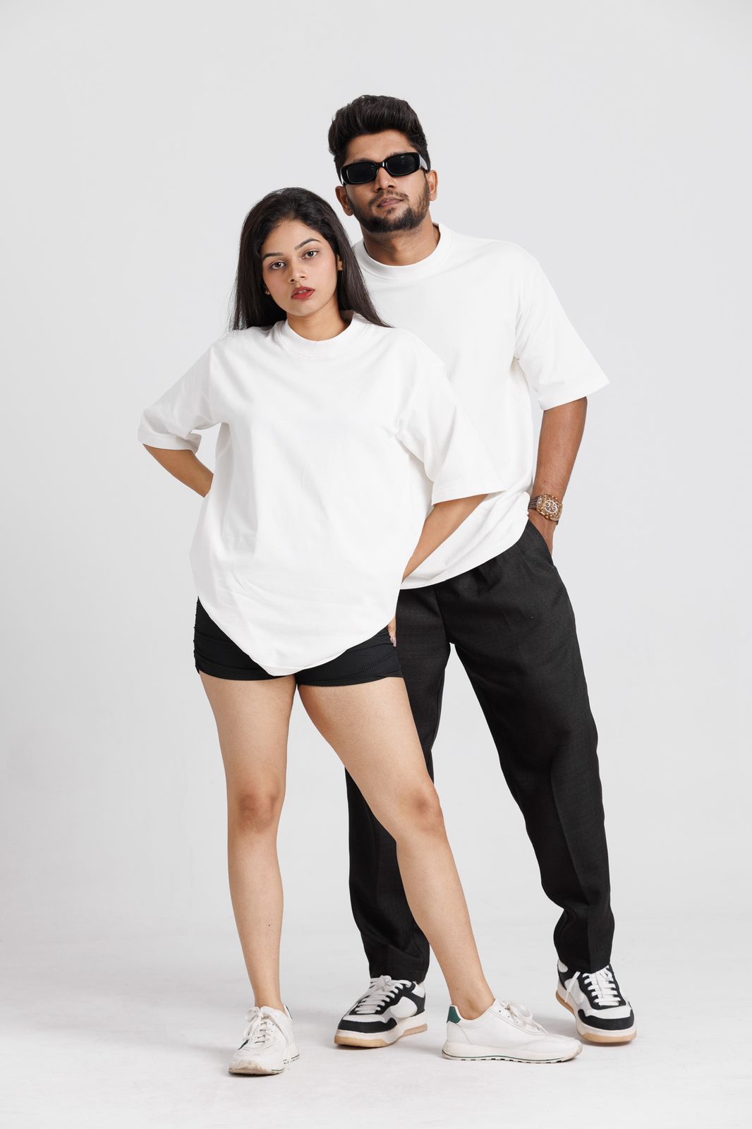 Two people wearing matching white t-shirts and black pants on a white background