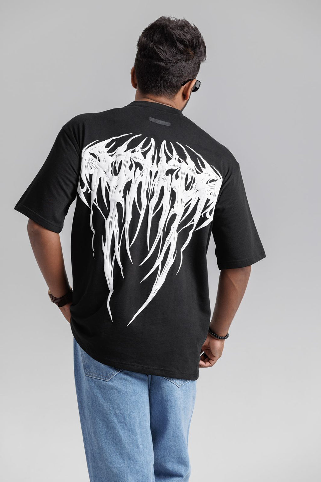 Person wearing a black t-shirt with white graphic design on the back against a gray background